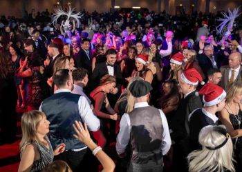 Guests dancing at a Moonlight & Mistletoe shared Christmas party night — packed dancefloor with Santa hats and production lighting