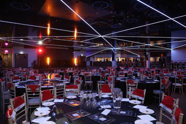 Wide view of the ICB Wolverhampton event space decorated for Christmas, showing rows of tables and balcony seating
